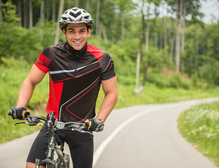 Young man in helmet riding on mountain bicycle on the forest road.の写真素材
