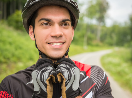 Cyclist male wearing his sports helmet and smiling.