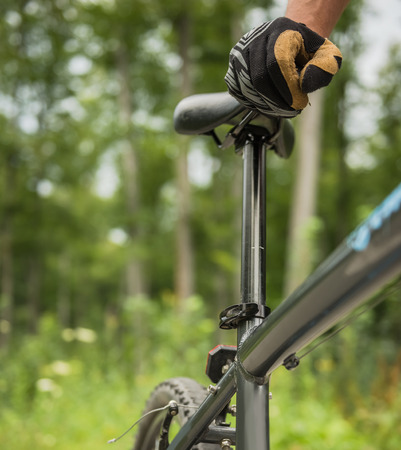 Young man with his bicycle on forest background. Close-up.