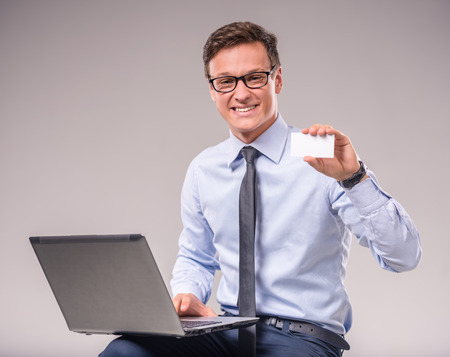 Portrait of a young businessman with a laptop on a gray backgroundの写真素材
