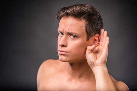 Portrait of emotional young man naked torso on black backgroundの写真素材