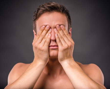 Portrait of emotional young man naked torso on black backgroundの写真素材