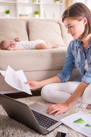 Young woman is working at home while her little baby is sleeping.の写真素材