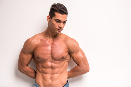 Young muscular man is standing on white background and looking down.の写真素材