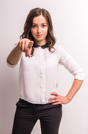 Young woman is standing on white background and pointing on you.の写真素材