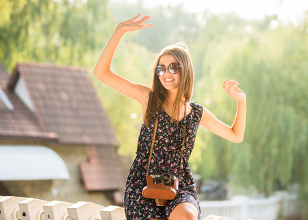 Beautiful woman is having fun with old fashioned camera. Summer, outdoors.の写真素材