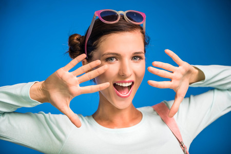 Young woman is having fun in funky glasses on blue background.の写真素材