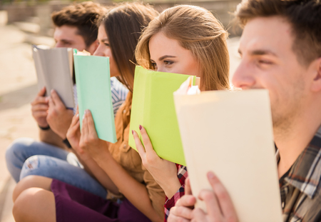 Young people, students walk outdoors. Sitting in the park and read a book.の写真素材