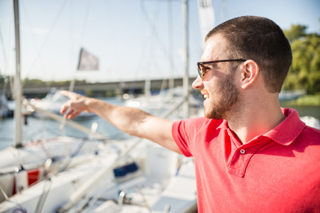 Young successful businessman pointing on the yacht.