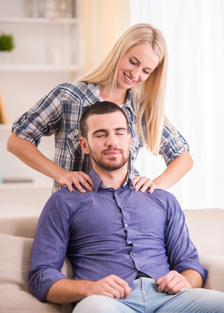Loving young couple sitting on the couch at home, look at the cameraの写真素材