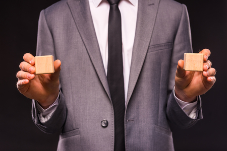 Creative idea. Young businessman presenting creative idea using wood cubes. Studio shooting isolated on Black backgroundの写真素材