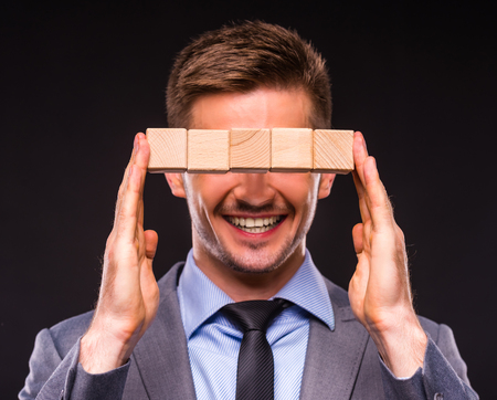Creative idea. Young businessman presenting creative idea using wood cubes. Studio shooting isolated on Black backgroundの写真素材