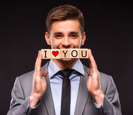 Creative idea. Young businessman presenting creative idea using wood cubes. Studio shooting isolated on Black backgroundの写真素材
