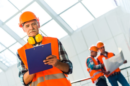 Portrait of a man construction builder in yellow helmet and vest the office center
