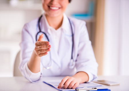 Portrait of a young beautiful woman doctor in a white coat in his officeの写真素材
