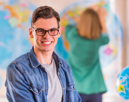 Portrait of a young man and woman chooses a place to travel through area, sitting in office travel agencyの写真素材