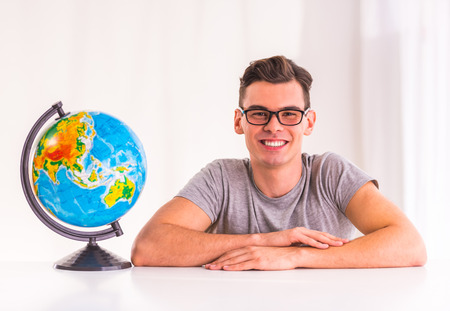 Portrait of a young man selects for the trip using a map sitting in office travel agencyの写真素材