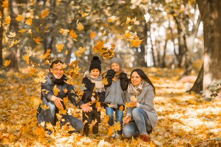 Happy family: mother father, son and daughter during a walk in the autumn parkの写真素材