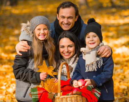 Happy family: mother father, son and daughter during a walk in the autumn parkの写真素材
