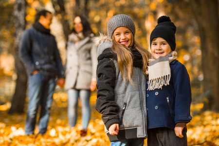 Happy family: mother father, son and daughter during a walk in the autumn parkの写真素材