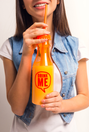 Portrait of a cheerful teenager girl drinking juice on a white backgroundの写真素材