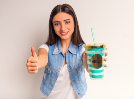 Portrait of a cheerful teenager girl drinking juice on a white backgroundの写真素材