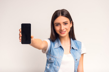 Portrait of cheerful girl teenager using the phone on a white backgroundの写真素材