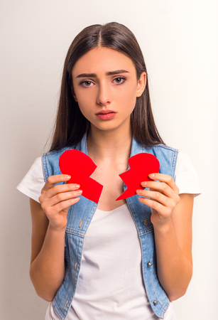 Portrait of a teenager girl in love with a paper heart on a white backgroundの写真素材