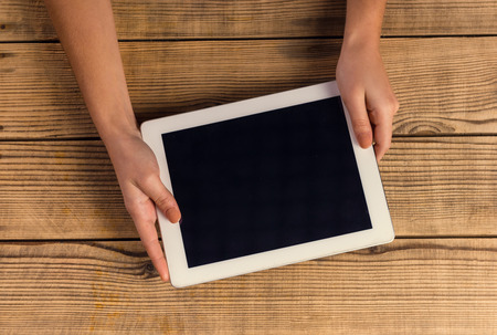 Hands close up using tablet on a wooden tableの写真素材