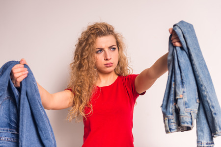 Young girl with curly hair, choose jeans, isolated on a gray backgroundの写真素材
