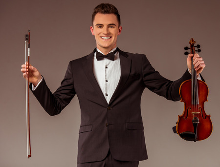 The young musician man playing violin on gray backgroundの写真素材