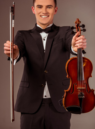 The young musician man playing violin on gray backgroundの写真素材