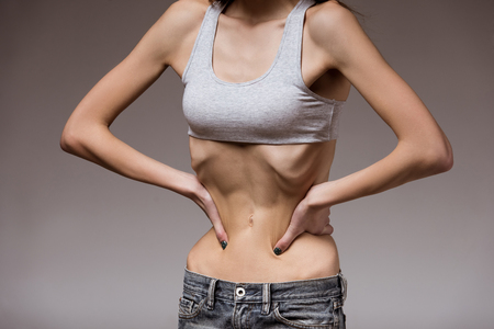 Very thin girl shows her skinny waist, covering his hands. Image is a close-upの写真素材