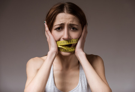 The girl suffering from anorexia wrapped tape measure close-up