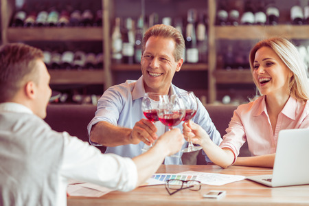 Business people are smiling, talking and clanging glasses of wine together during business lunchの写真素材