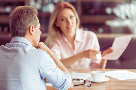 Beautiful business woman is holding a document and explaining business affair to man during business meeting at the restaurantの写真素材