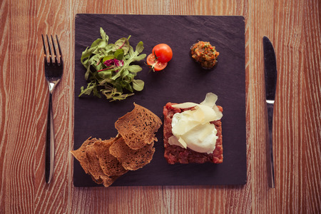 Top view of light dish perfect for lunch served on black square plate, on the wooden table