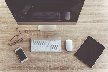 Top view of modern computer, digital tablet and smartphone for business people working in office, on wooden tableの写真素材