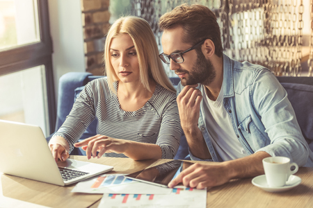 Business couple in casual wear is using a laptop and discussing affairs while working in the officeの写真素材