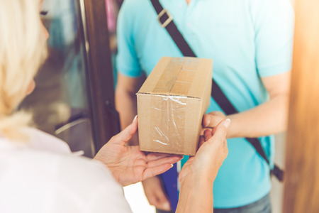 Cropped image of beautiful mature woman getting the delivery from handsome worker while moving to the new apartmentの写真素材
