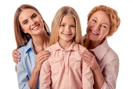 Portrait of happy little girl, her beautiful mom and grandma looking at camera and smiling, isolated on whiteの写真素材