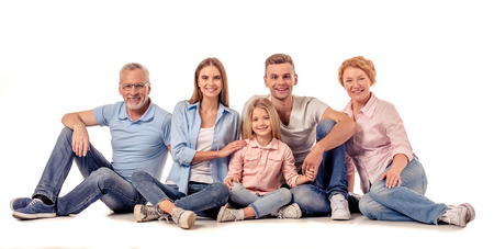 Portrait of cute little girl, her beautiful parents and grandparents looking at camera and smiling while sitting on a white backgroundの写真素材