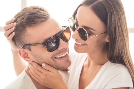 Portrait of beautiful young couple in sun glasses hugging and smilingの写真素材