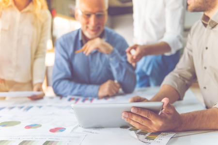 Cropped image of beautiful business people using a digital tablet, studying documents and smiling...
