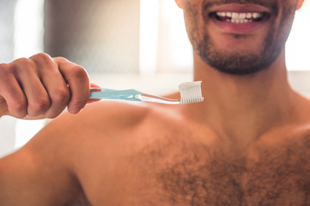 Cropped image of handsome Afro American man holding a toothbrush with toothpaste and smilingの写真素材
