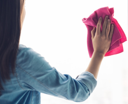 Cropped image of beautiful young woman using a rag while cleaning windows