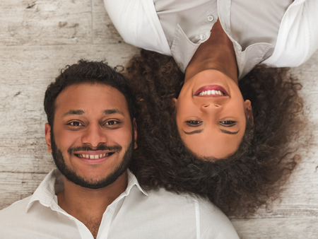 Top view of beautiful Afro American couple looking at camera and smiling while lying together on the...
