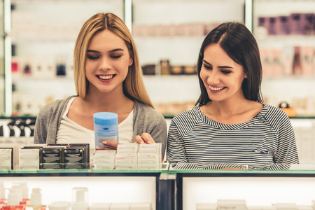 Beautiful girls are choosing cosmetics and smiling while doing shopping in the mallの写真素材