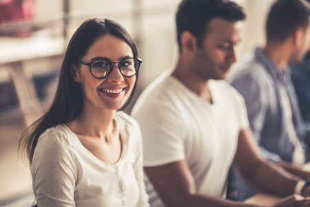 Successful young business people are working in office. Girl is looking at camera and smilingの写真素材