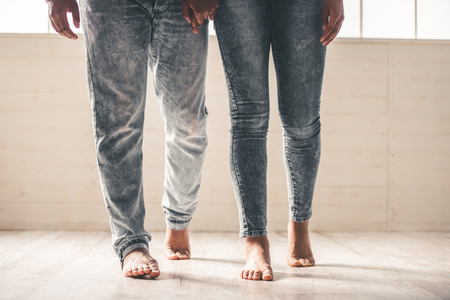 Afro American couple barefoot and in jeans holding hands, croppedの写真素材